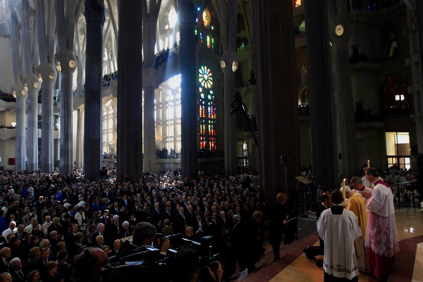 La pop et d'autres prêtres se tiennent devant la Sagrada Familia pour célébrer un service devant une foule nombreuse