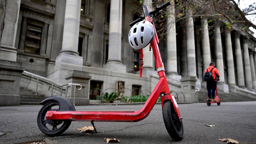 An e-scooter stands on a footpath.