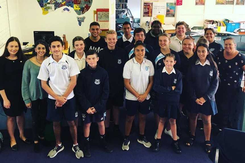 Students stand in a classroom.