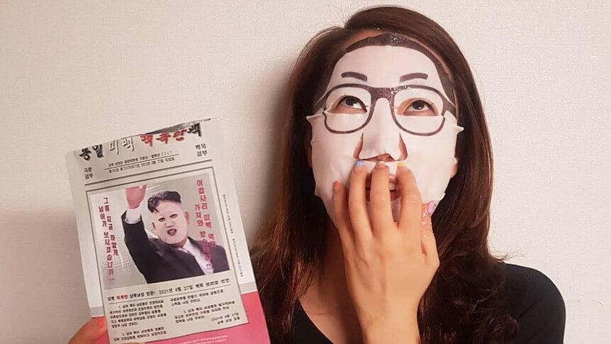 An image of someone using the Kim Jong-un face masks, it is a white mask with glasses supposed to look like Kim Jong-un.