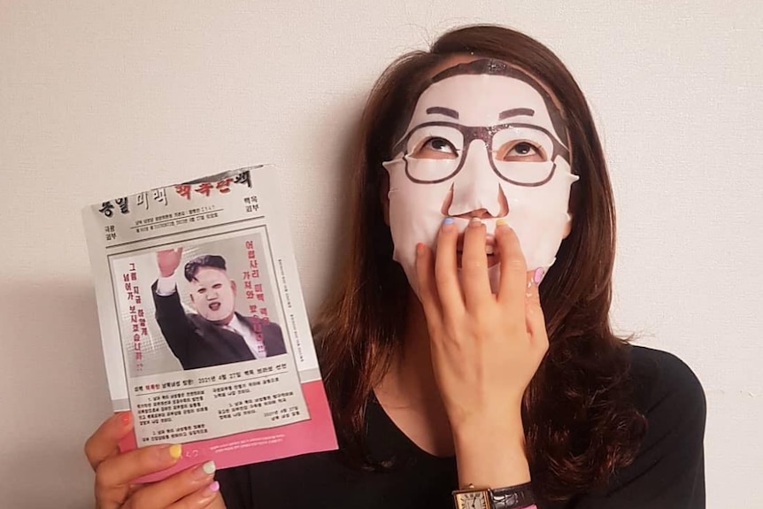An image of someone using the Kim Jong-un face masks, it is a white mask with glasses supposed to look like Kim Jong-un.
