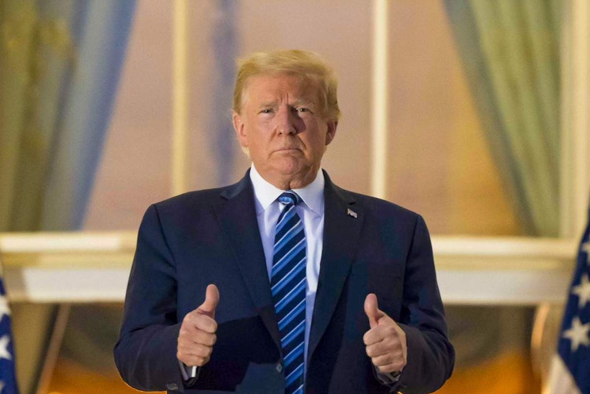 Donald Trump stands outside the White House giving a thumbs up