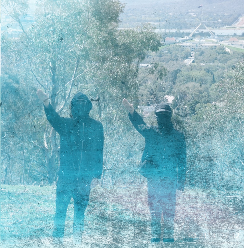 Two men in balaclavas give a fascist salute with Parliament House in the background.