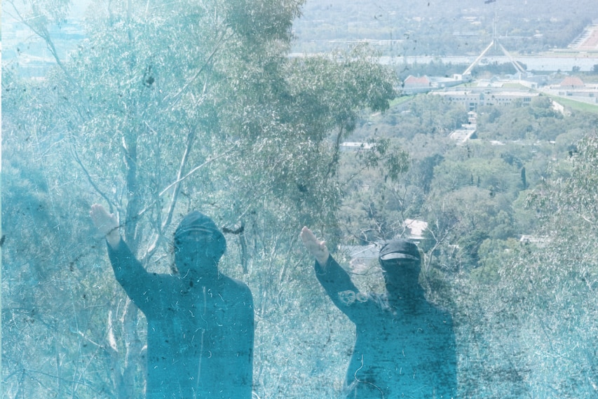 Two men in balaclavas give a fascist salute with Parliament House in the background.