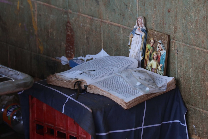 A Bible in Anmatyerre and English and religious icons rest by Kathleen Ngale's bedside.