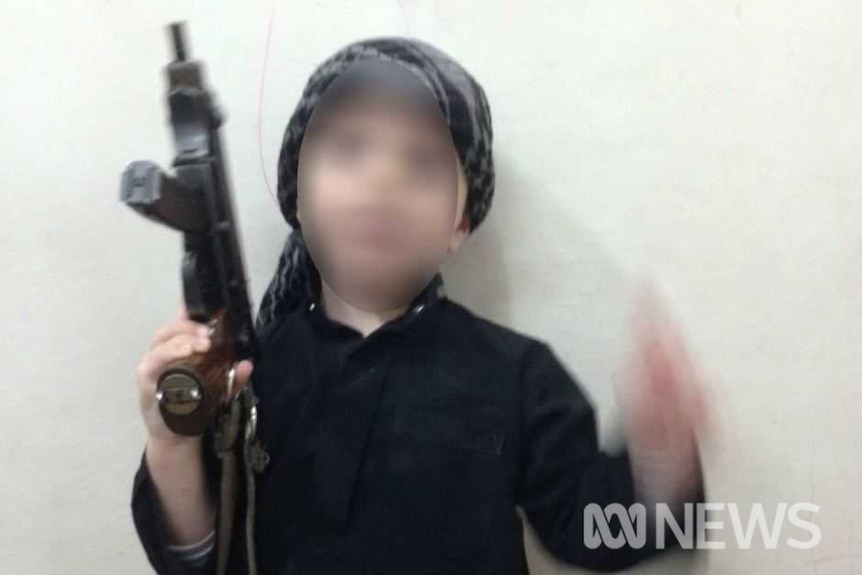 Child with blurred face holds up a gun.