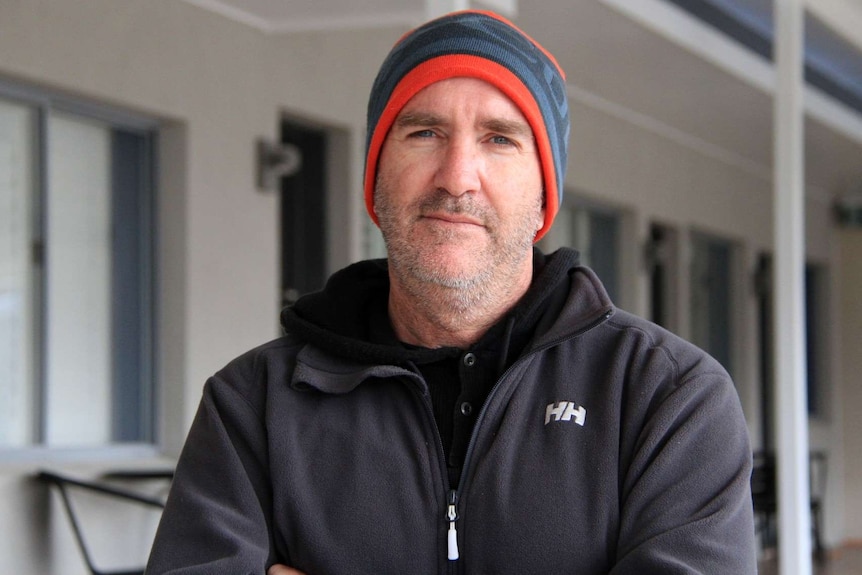 Michael Jensen stands, with arms crossed, outside his motel in Stanthorpe.