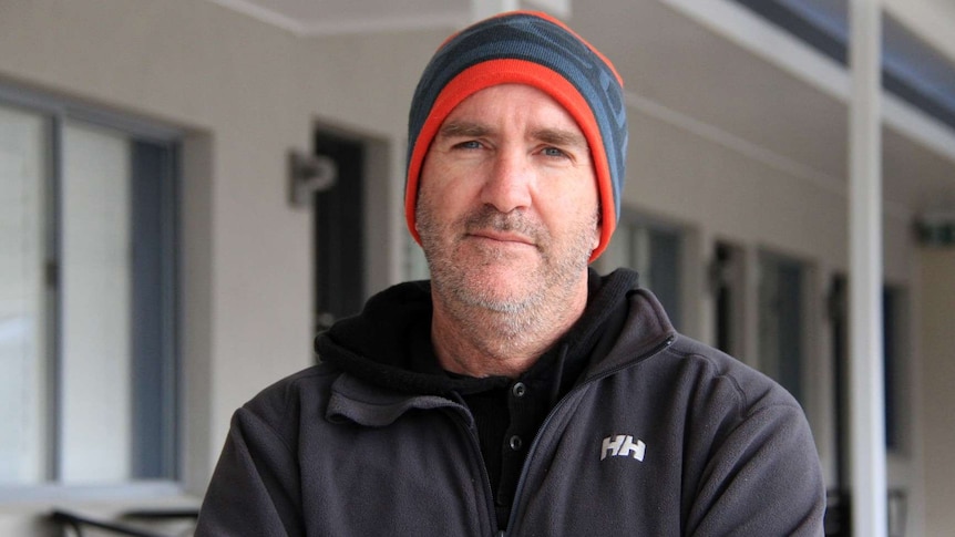 Michael Jensen stands, with arms crossed, outside his motel in Stanthorpe.