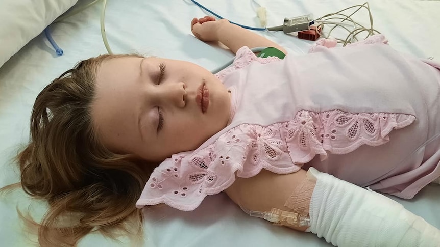 a young girl lying in a hospital bed with medical cords around her
