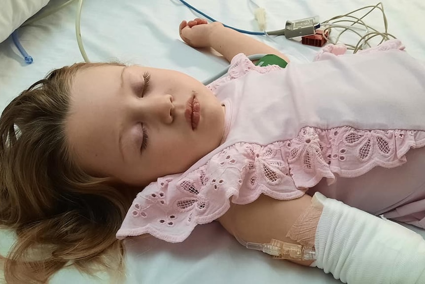 a young girl lying in a hospital bed with medical cords around her