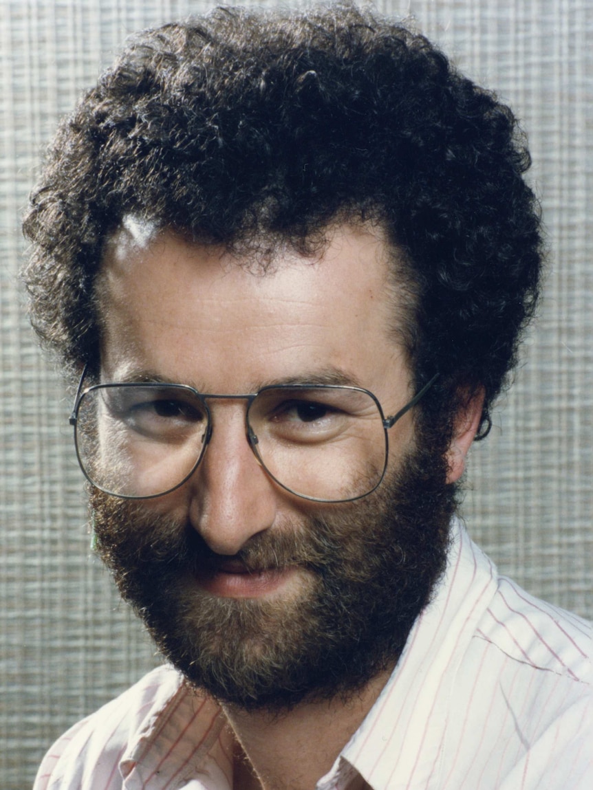 A photo of Jon Faine, where he has a thick brown hair and large glasses.