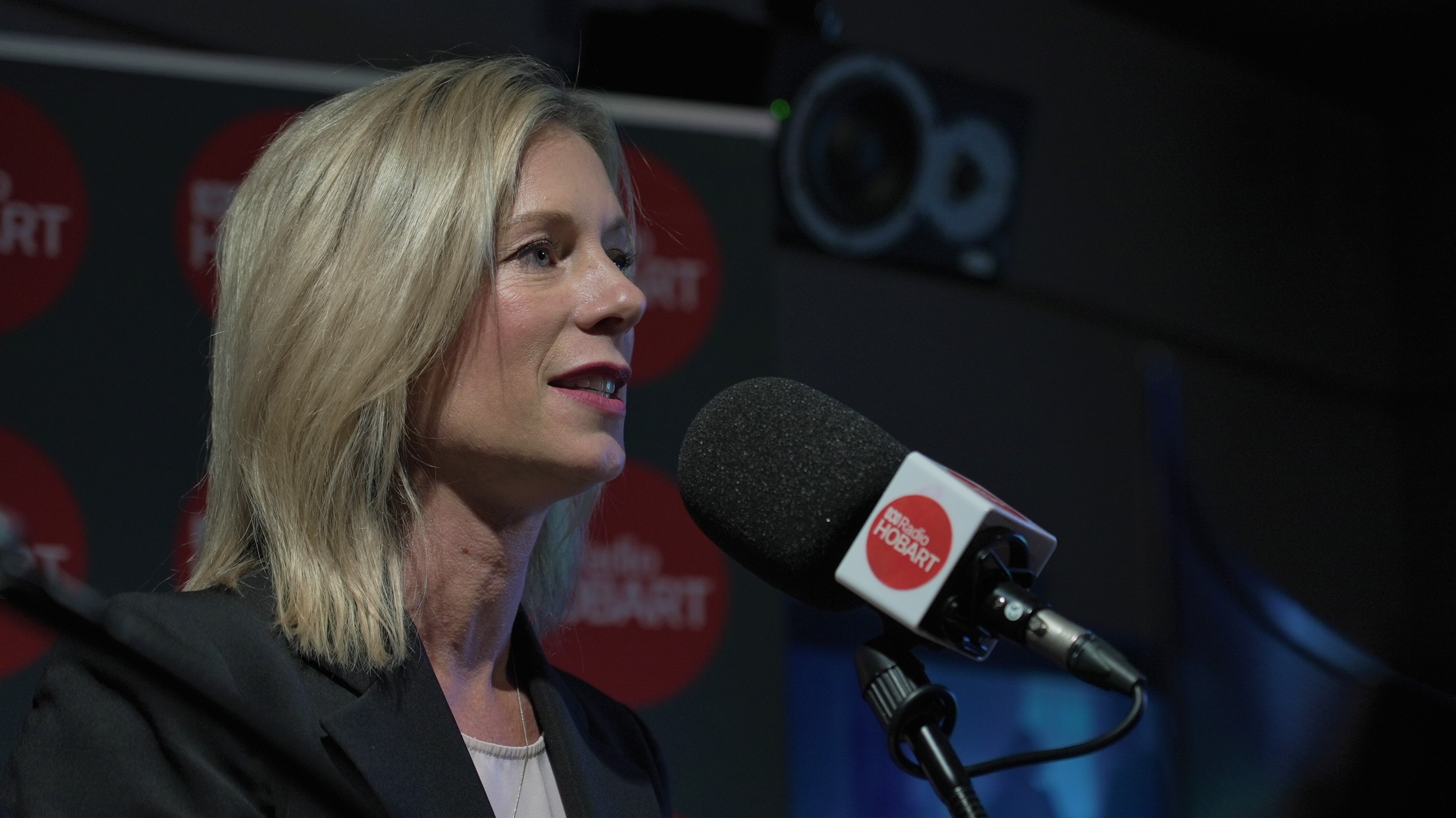 A blonde woman stands in front of a microphone that says Radio Hobart.