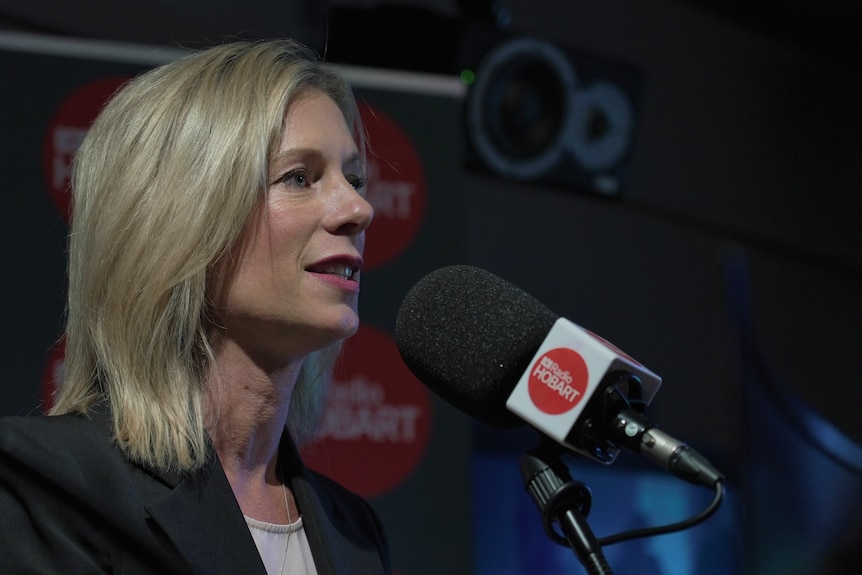 A blonde woman stands in front of a microphone that says Radio Hobart.