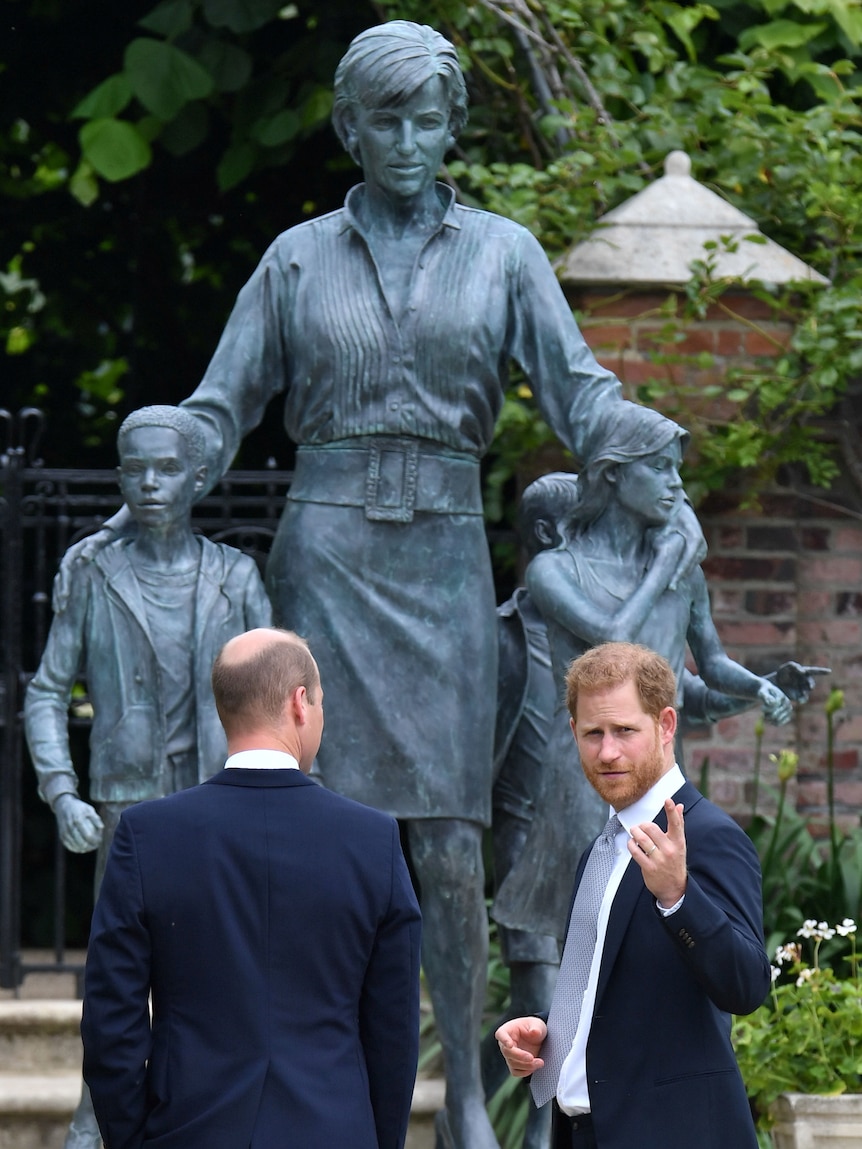 Prince Harry points as he and brother William unveil a statue of their mother Diana.