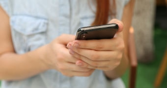 Close-up shot of woman in light denim top holding smartphone