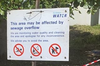 A sign warning that the water may be affected by sewage