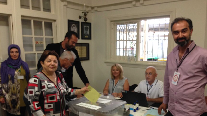 A Turkish Australian woman casts her vote into the ballot box.