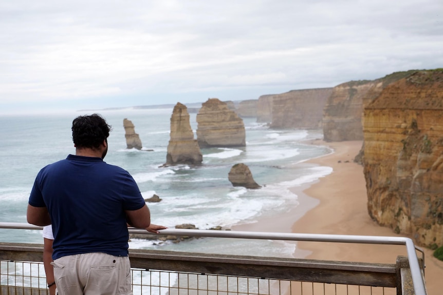 A man stands at a lookout above the Twelve Apostles.