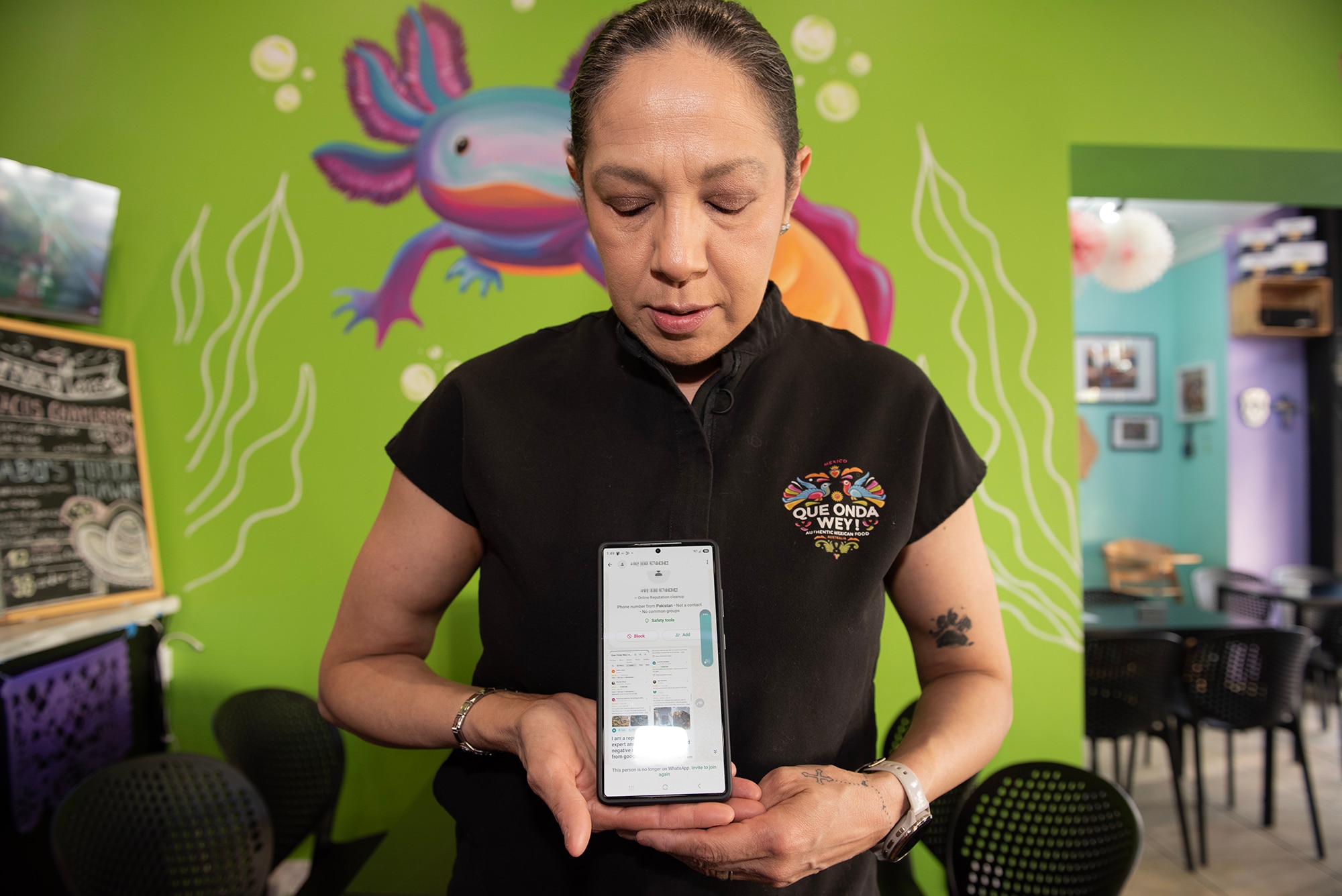Woman holds a mobile phone in colourful cafe