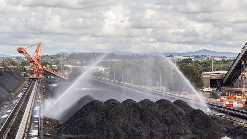 Water is sprayed over a large pile of coal.