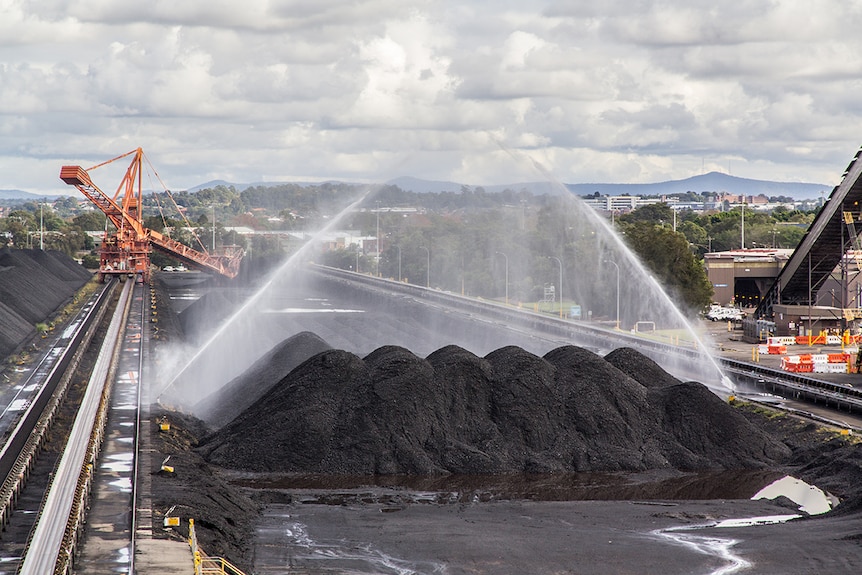 Water is sprayed over a large pile of coal.