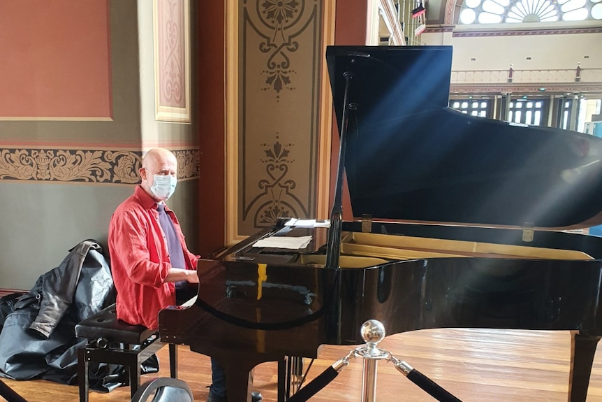 A man playing the piano inside the Carlton Royal Exhibition Building