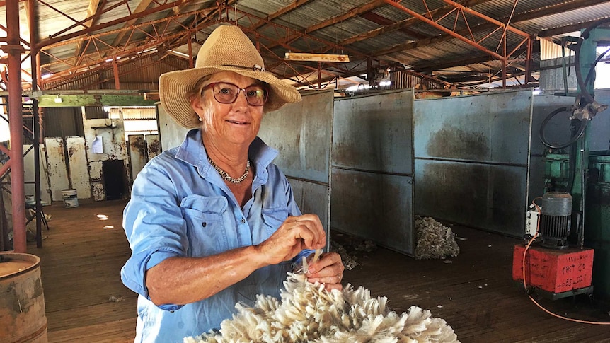 Grazier Carol Godfrey inspects a fleece in Tinnenburra's historic shearing shed.