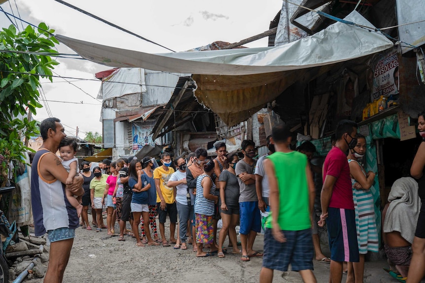 A long line of people in San Roque, some wearing face masks