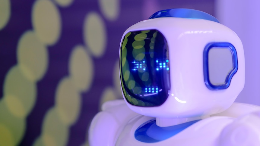 Close up of the head of a blue and white humanoid robot with a screen for a face.