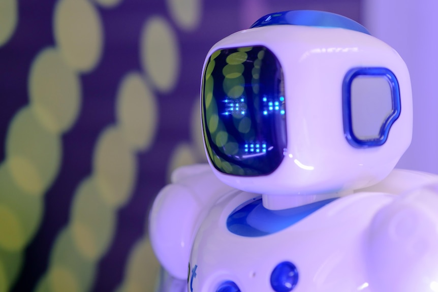 Close up of the head of a blue and white humanoid robot with a screen for a face.