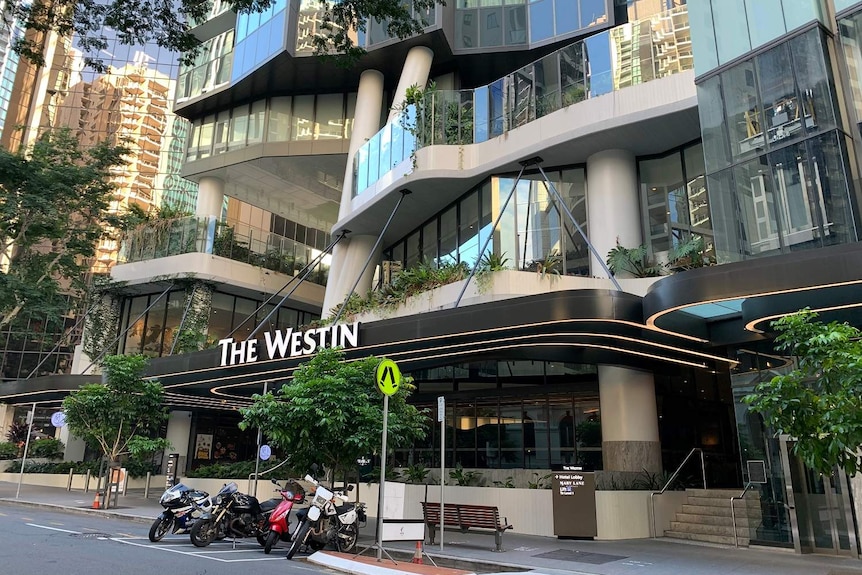 The Westin hotel in Brisbane, with shiny glass and motorbikes parked out front.