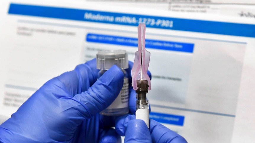 Gloved hands of a nurse prepares a shot as a study of a COVID-19 vaccine