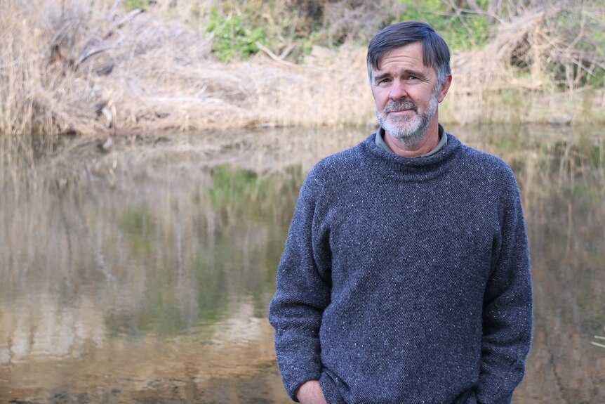 Water ecologist Chris Bobbi standing next to a river.