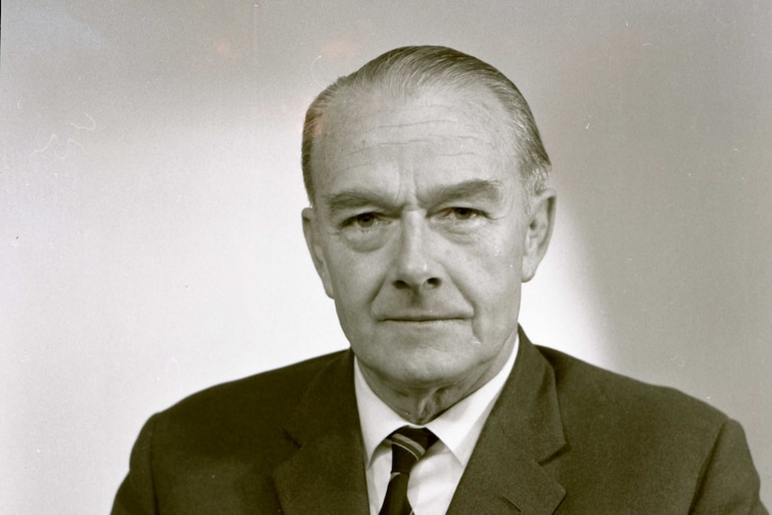 An historic black and white head and shoulders image of an older man in a suit and tie.
