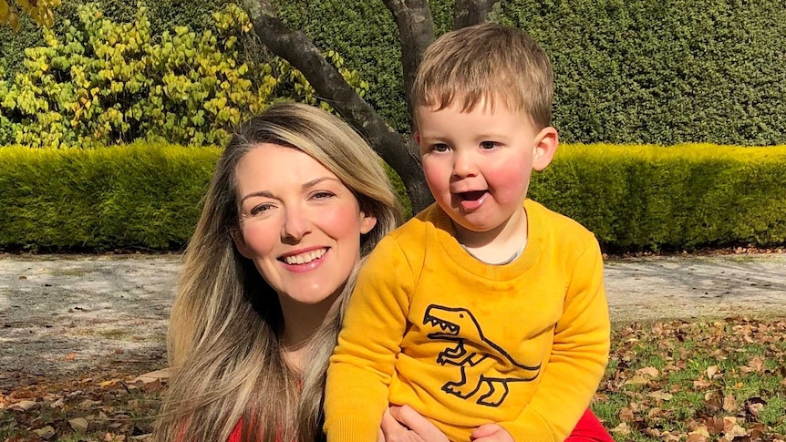 Woman in red shirt holding toddler in yellow shirt