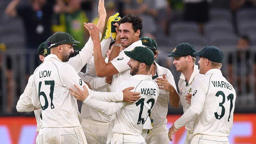 Mitchell Starc offers hi-fives to teammates after getting a wicket in Perth