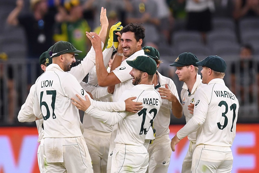 Mitchell Starc offers hi-fives to teammates after getting a wicket in Perth
