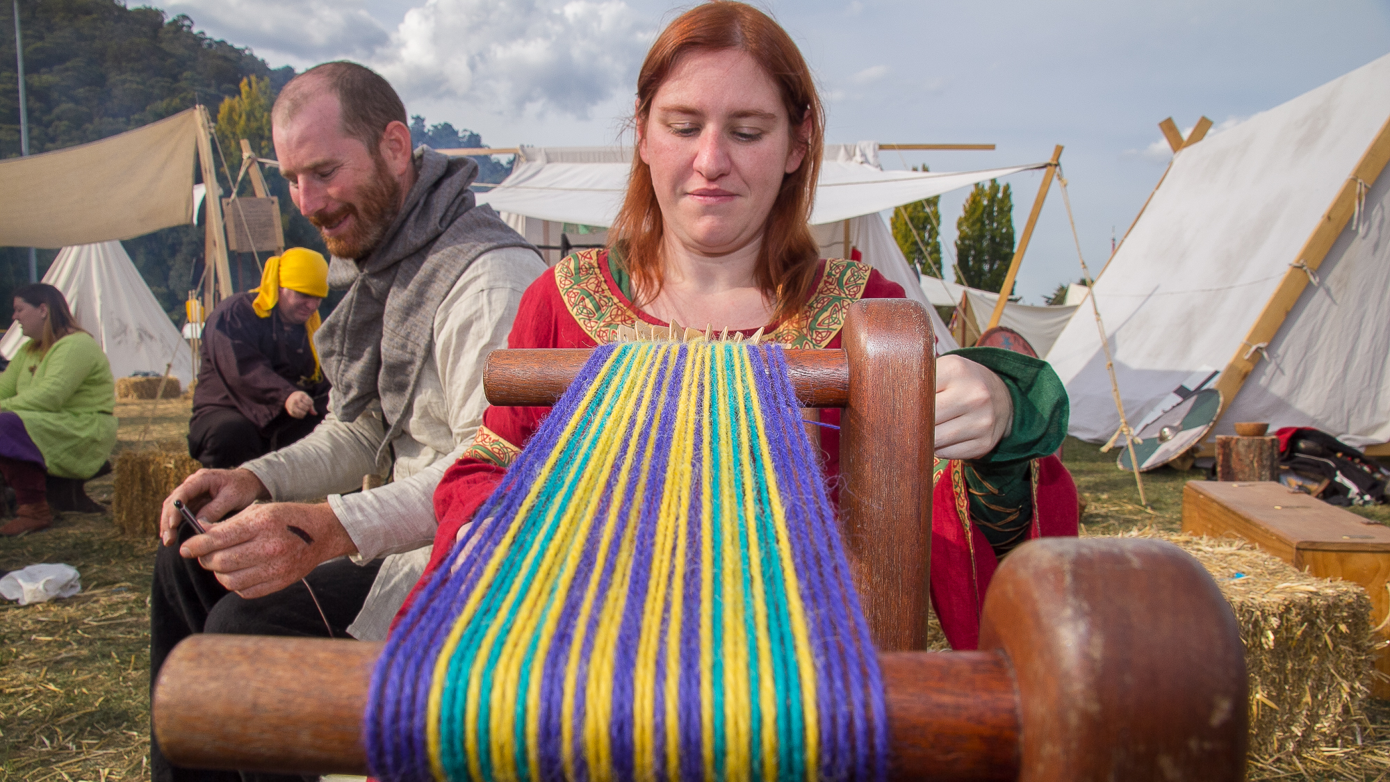A woman weaving colourful wool on medieval loom