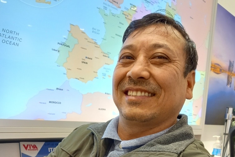 A man smiling in front of a map projected on a screen