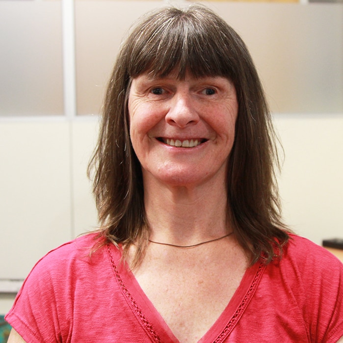 A woman with shoulder-length brown hair smiles at the camera