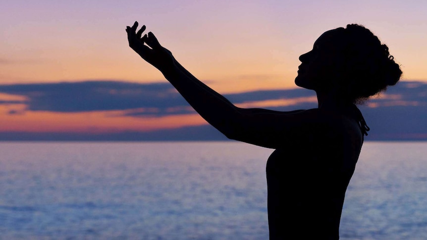 a silhouette of a woman by the sea at sunset