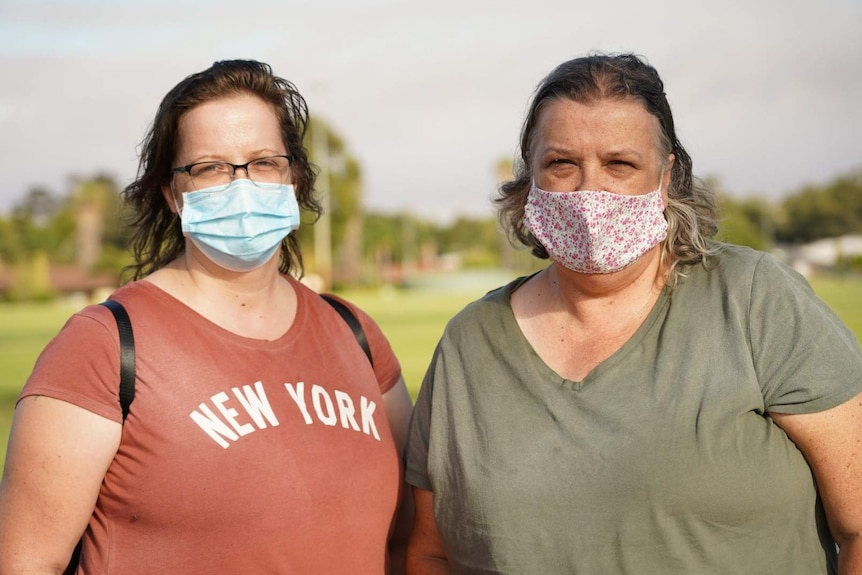 The Kings stand on the road, smoke in the background, both are wearing masks.