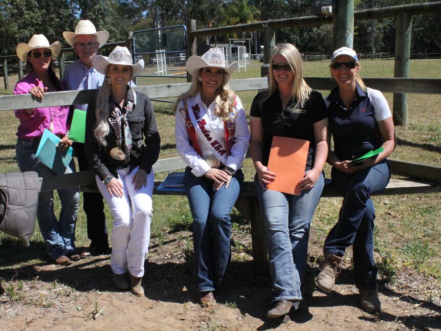 The six judges sit on the fence surrounding the horse arena at Nerang Pony Club