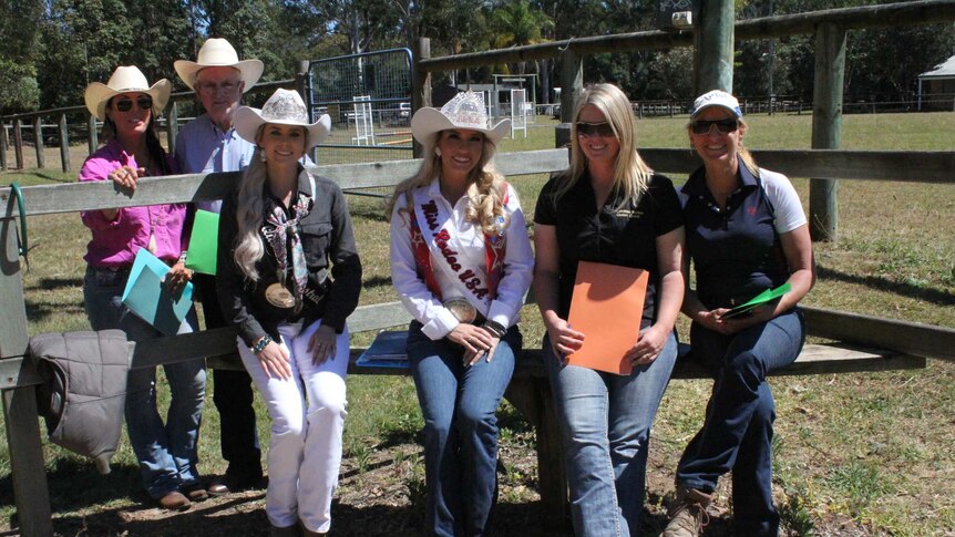 The six judges sit on the fence surrounding the horse arena at Nerang Pony Club