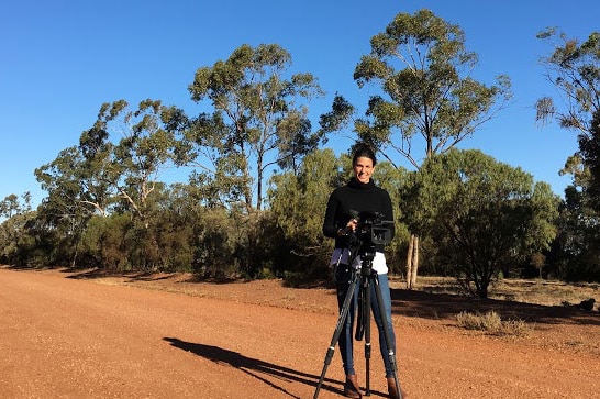 Ashlynne McGhee with camera on tripod filming in outback Queensland for Story Hunters.