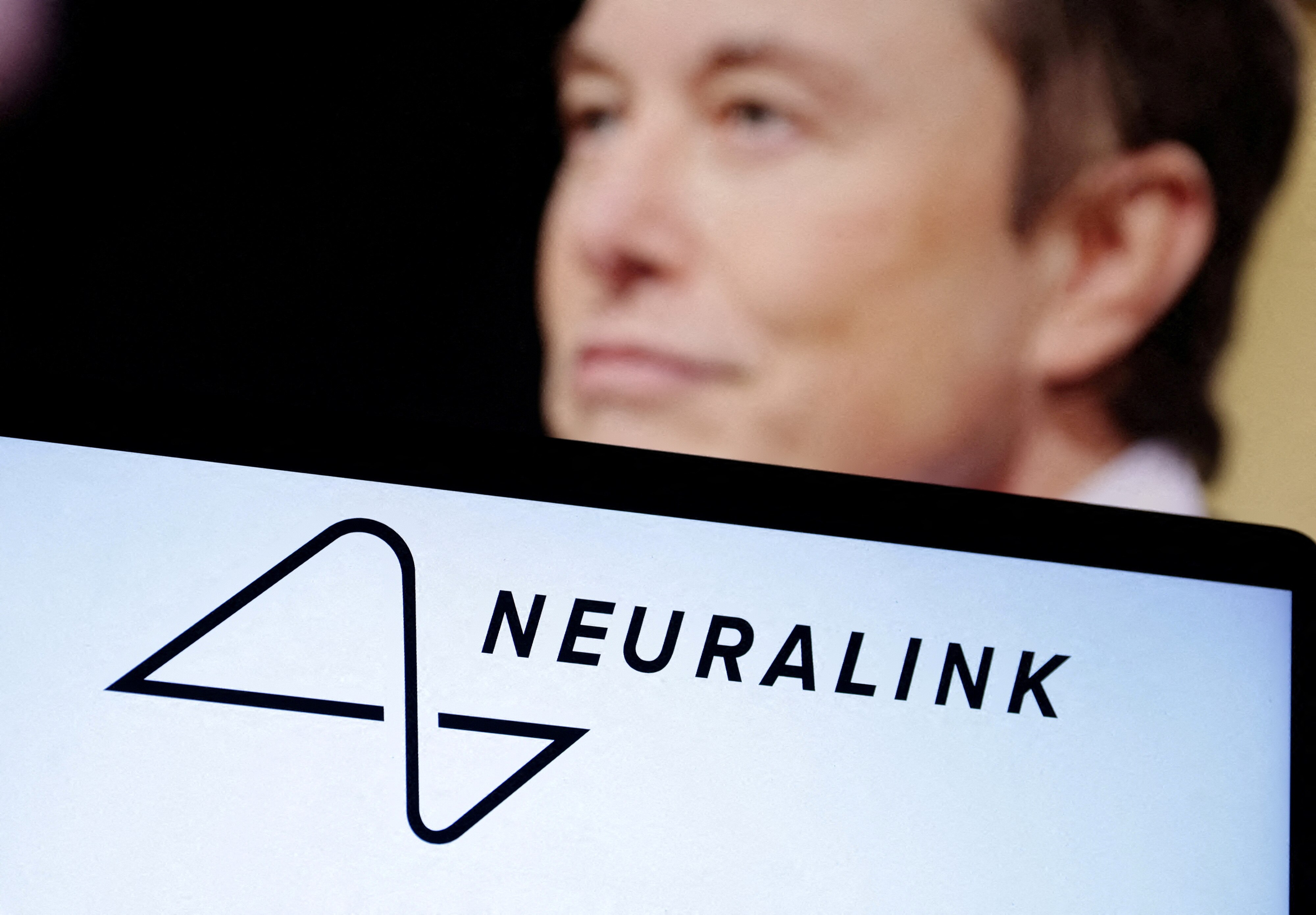 Elon Musks' face is pictured behind the logo for Neuralink.