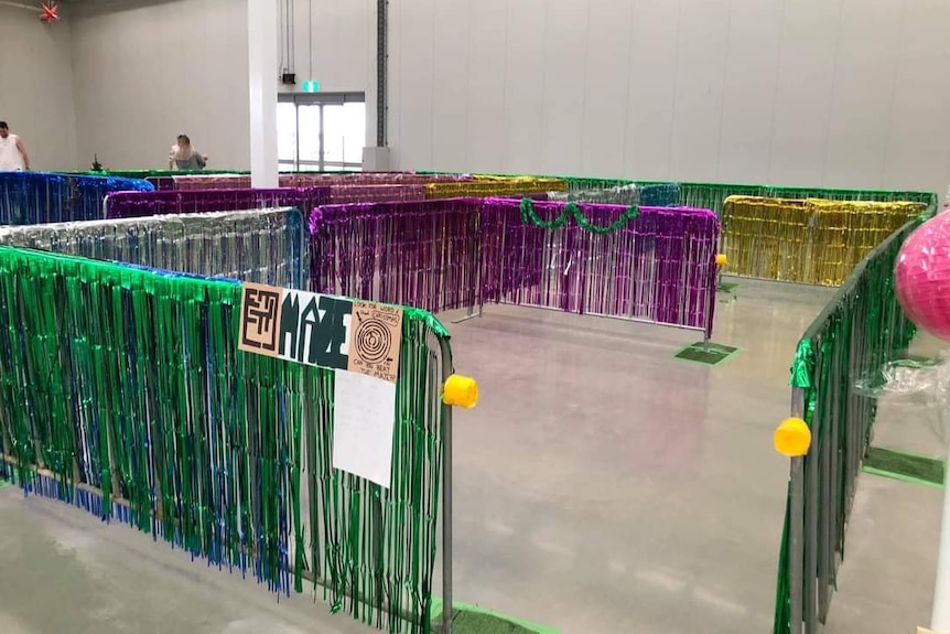 A maze made from crowd fencing covered in tinsel in a large warehouse.