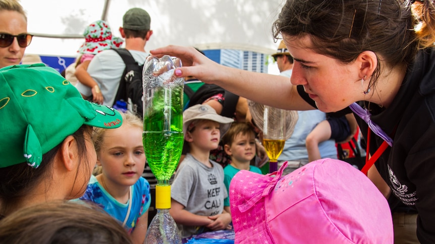 Young budding minds help a University of Queensland student conduct an experiment.