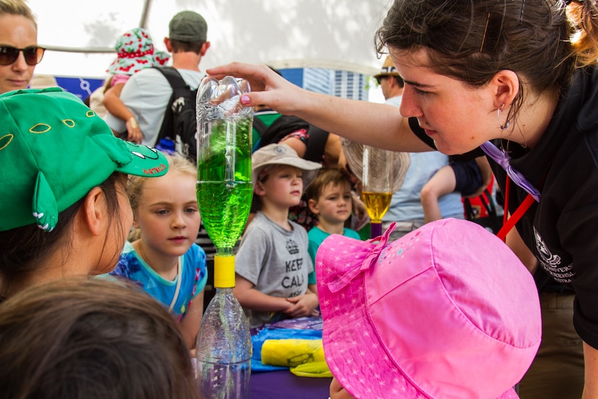 Young budding minds help a University of Queensland student conduct an experiment.