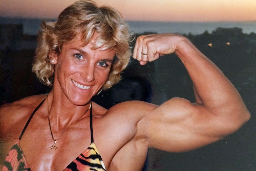 a female body builder pulls a muscle pose.